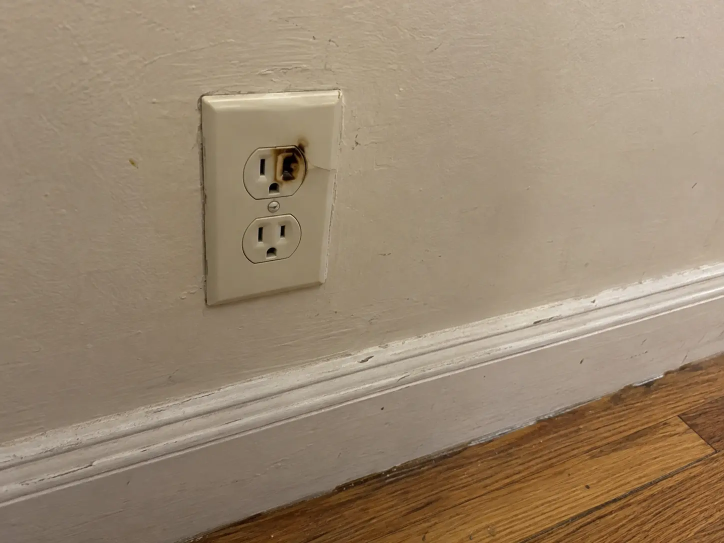 Scorched duplex outlet on a plaster wall