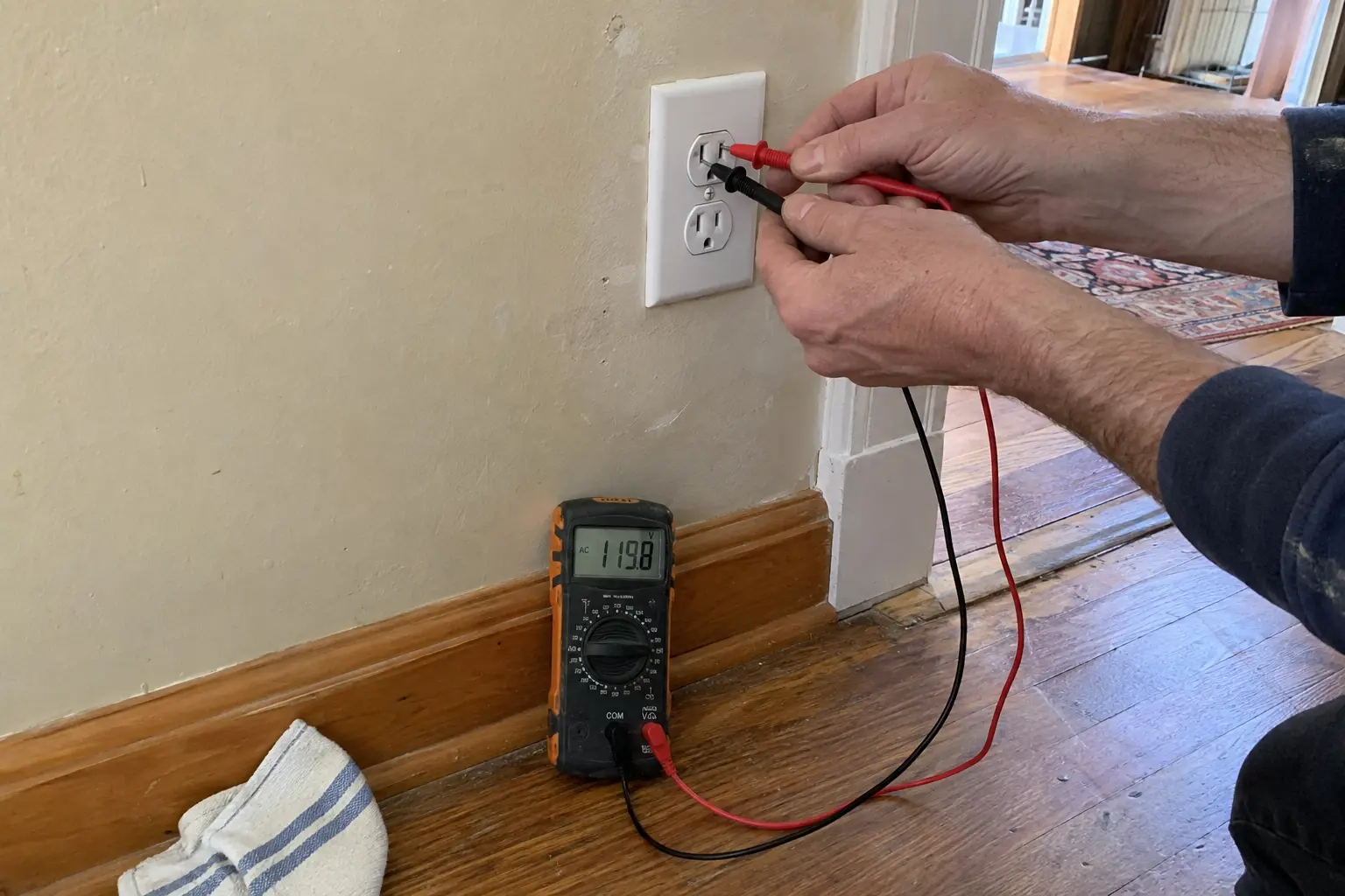 Electrician testing a replaced outlet with a multimeter