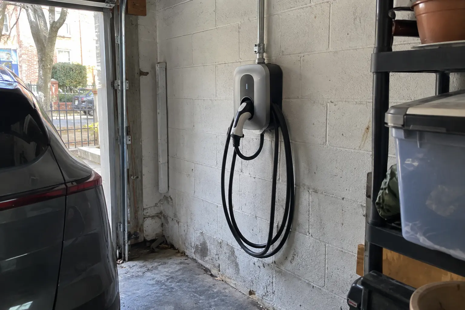 Wall-mounted EV charger beside a car in a Brooklyn garage